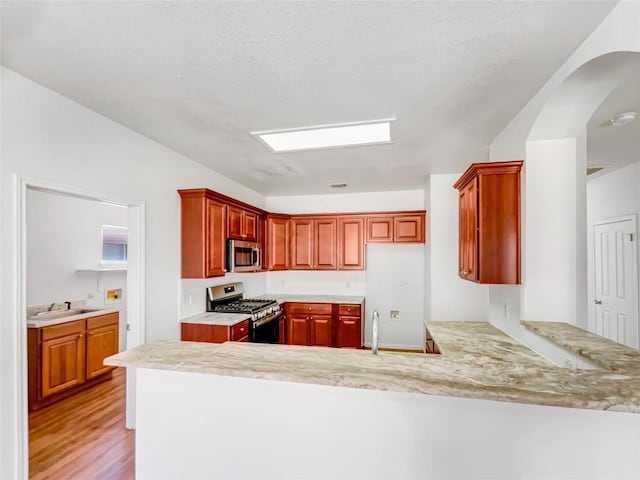 3128 Flinders Reef Ln, Austin, TX 78728 - kitchen with appliances with stainless steel finishes, a peninsula, and light wood-type flooring
