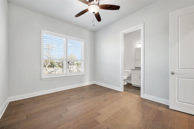 unfurnished bedroom with ceiling fan, baseboards, ensuite bath, and dark wood-style floors