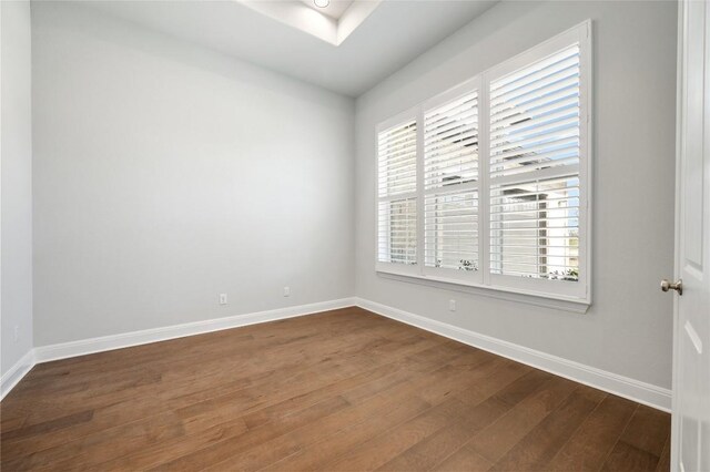 unfurnished room featuring a skylight, baseboards, and dark wood-style floors