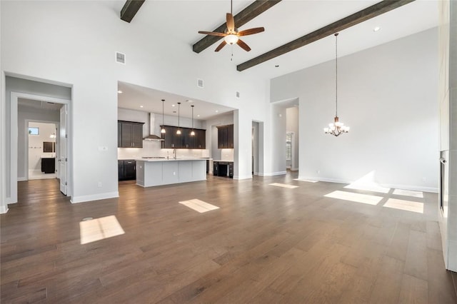 unfurnished living room with dark wood-style floors, visible vents, baseboards, beamed ceiling, and ceiling fan with notable chandelier