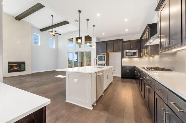 kitchen featuring visible vents, a tiled fireplace, light countertops, beam ceiling, and appliances with stainless steel finishes