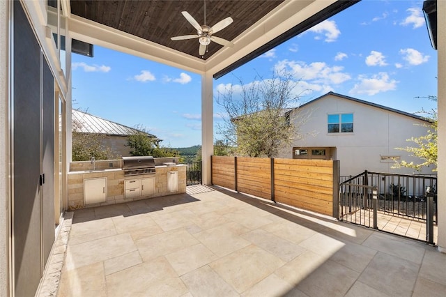 view of patio / terrace with ceiling fan, area for grilling, fence, and an outdoor kitchen