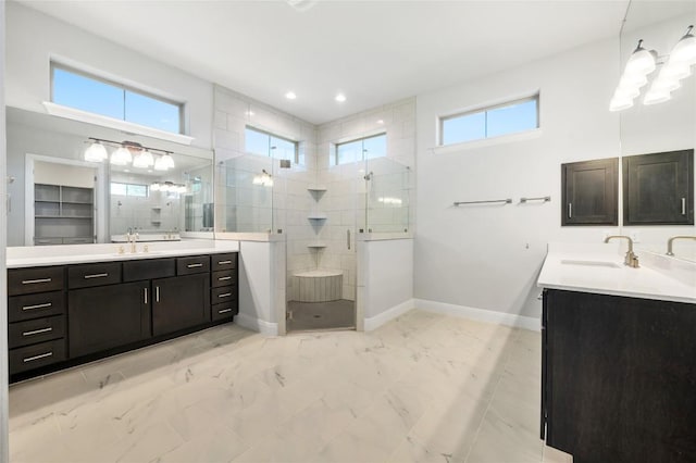 bathroom featuring plenty of natural light, two vanities, a stall shower, and a sink