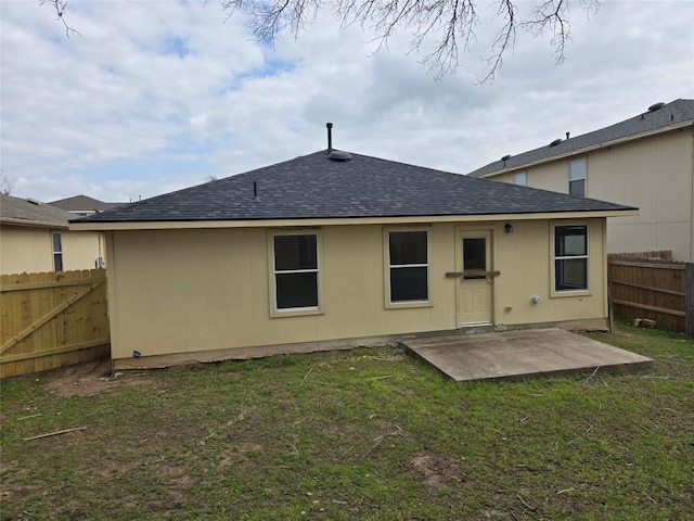 rear view of house featuring a patio, a yard, fence, and roof with shingles