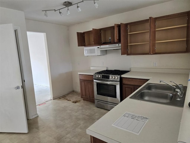 kitchen featuring a sink, under cabinet range hood, light floors, white microwave, and stainless steel range with gas stovetop