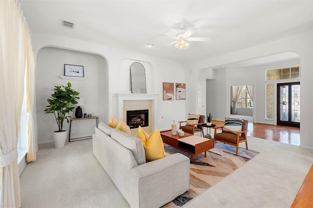 living area featuring a ceiling fan, a fireplace, visible vents, and baseboards