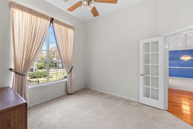 carpeted empty room featuring a ceiling fan and baseboards