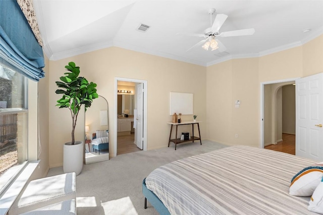 bedroom featuring visible vents, light colored carpet, lofted ceiling, ornamental molding, and arched walkways