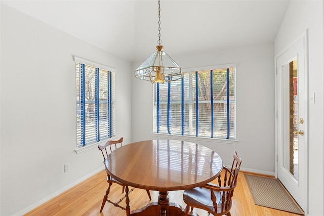 dining room with a chandelier, baseboards, and light wood-style flooring