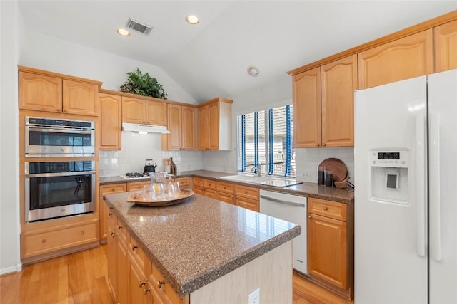 kitchen with visible vents, light brown cabinetry, under cabinet range hood, white appliances, and lofted ceiling