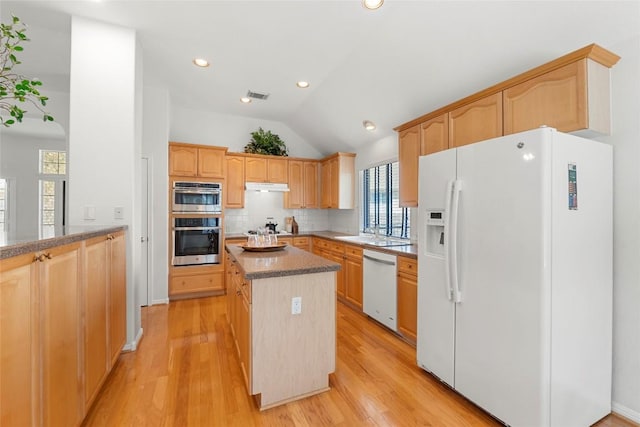 kitchen featuring visible vents, a kitchen island, light wood-type flooring, decorative backsplash, and white appliances