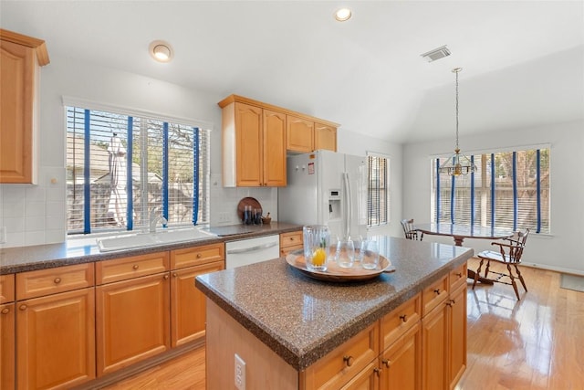 kitchen featuring white appliances, visible vents, light wood finished floors, and a sink