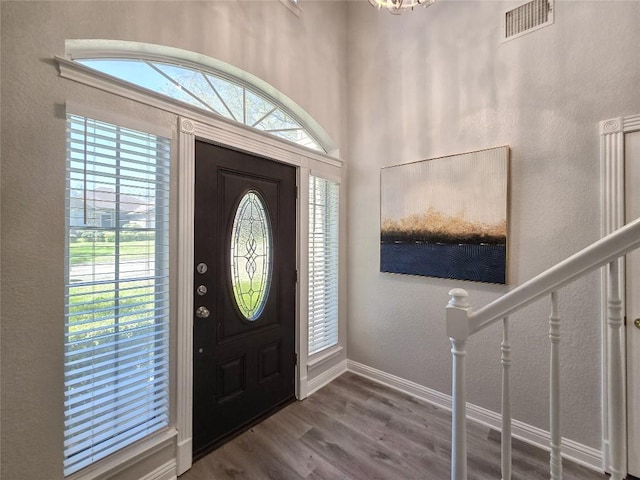 foyer entrance featuring visible vents, baseboards, wood finished floors, stairs, and a textured wall