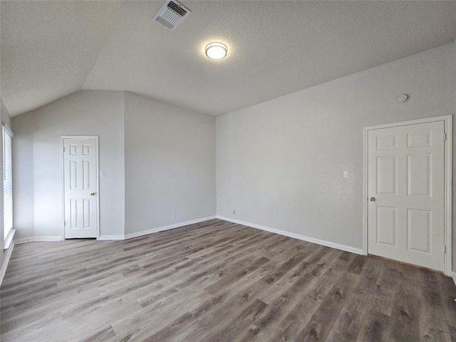 interior space featuring vaulted ceiling, wood finished floors, visible vents, and baseboards