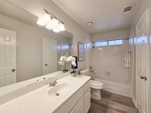 full bath with visible vents, a textured ceiling, toilet, and wood finished floors