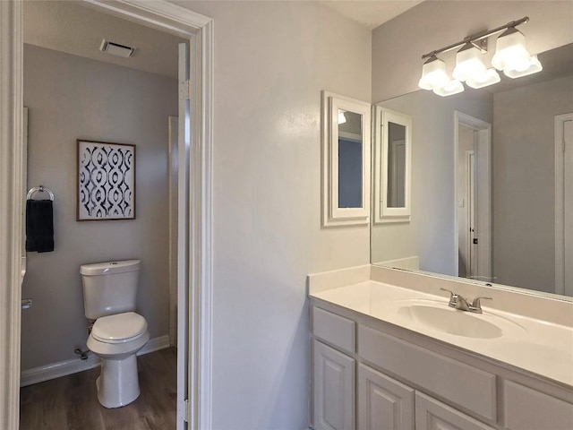 bathroom featuring visible vents, toilet, wood finished floors, baseboards, and vanity