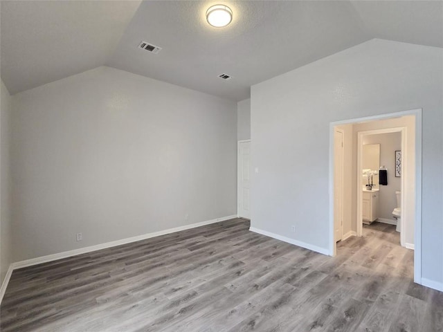 unfurnished bedroom with visible vents, wood finished floors, and vaulted ceiling