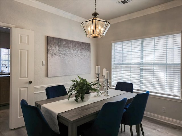 dining room with crown molding, a notable chandelier, baseboards, and light wood finished floors