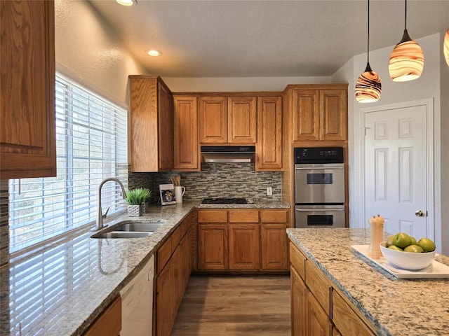 kitchen with stainless steel double oven, gas stovetop, white dishwasher, a sink, and under cabinet range hood