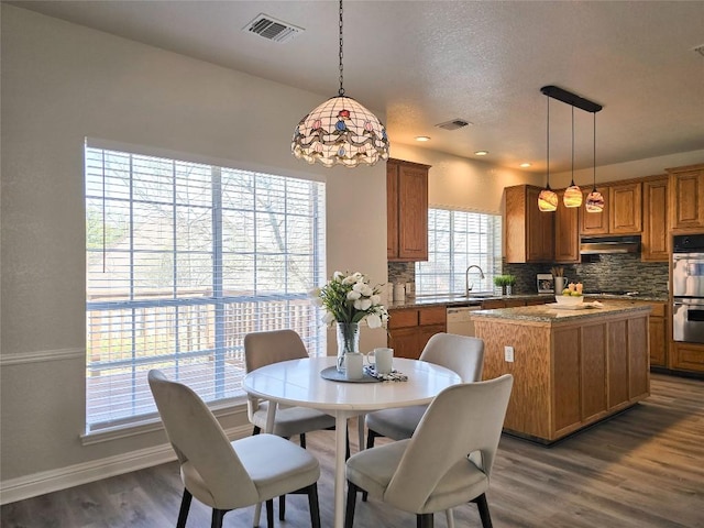 dining area with dark wood finished floors, visible vents, a textured ceiling, and baseboards