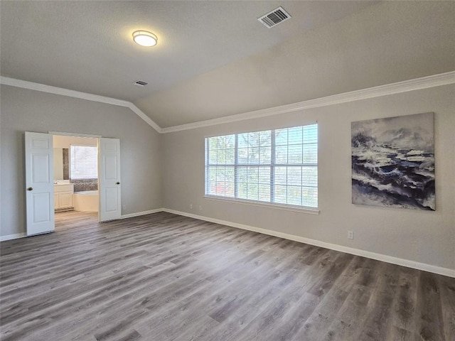 empty room with baseboards, crown molding, lofted ceiling, and wood finished floors