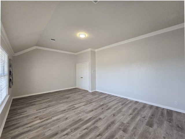 spare room featuring baseboards, crown molding, lofted ceiling, and wood finished floors