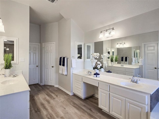 full bath with wood finished floors, two vanities, and a sink