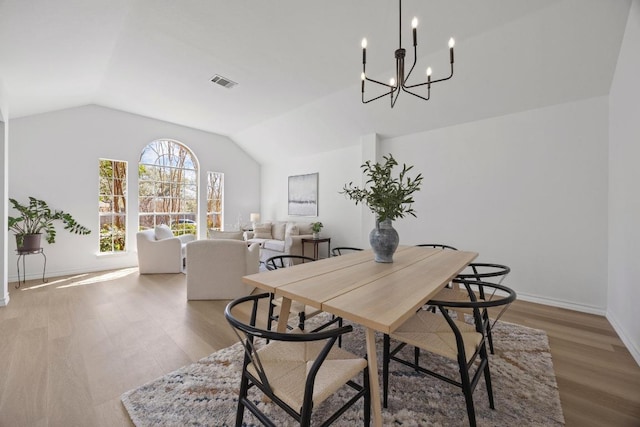 dining area featuring visible vents, baseboards, wood finished floors, and vaulted ceiling