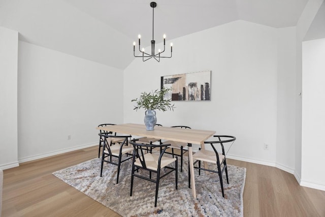 dining area featuring wood finished floors, baseboards, and vaulted ceiling