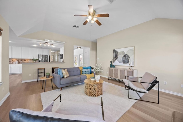 living room with visible vents, light wood-style flooring, baseboards, and vaulted ceiling