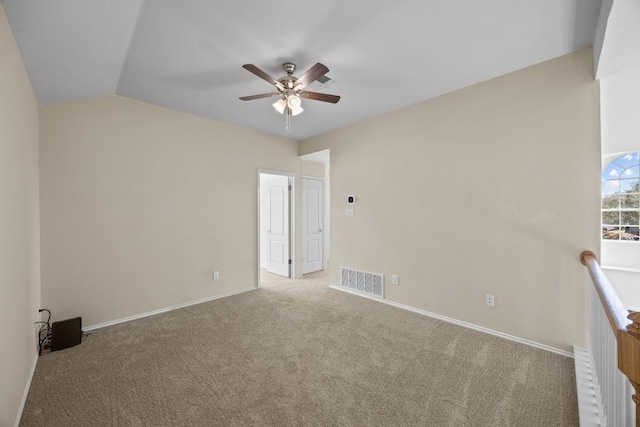 carpeted empty room with a ceiling fan, vaulted ceiling, baseboards, and visible vents