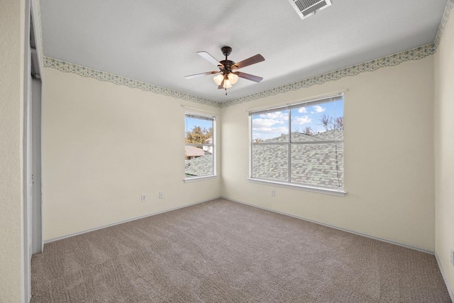 unfurnished room featuring visible vents, carpet, and a ceiling fan