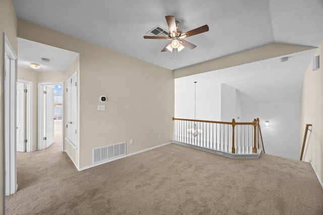 spare room featuring visible vents, carpet floors, lofted ceiling, and ceiling fan with notable chandelier