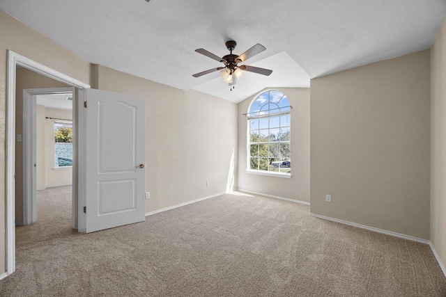 carpeted spare room featuring lofted ceiling, baseboards, and a wealth of natural light