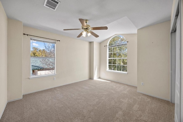 carpeted empty room featuring visible vents, baseboards, a ceiling fan, and vaulted ceiling