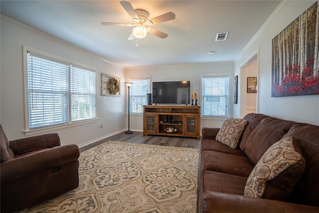 living area featuring visible vents, ornamental molding, a ceiling fan, wood finished floors, and baseboards