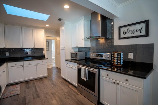 kitchen featuring dark countertops, appliances with stainless steel finishes, white cabinets, wall chimney exhaust hood, and dark wood-style flooring