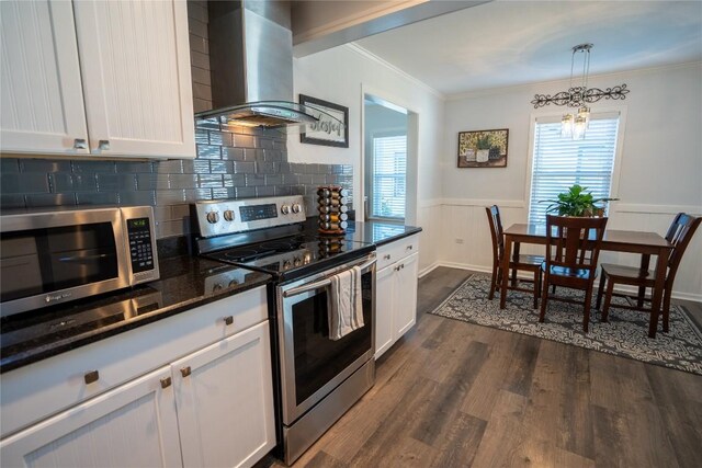 kitchen featuring wainscoting, stainless steel appliances, white cabinetry, wall chimney exhaust hood, and dark wood-style flooring