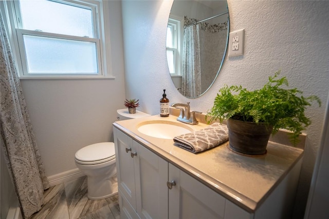 bathroom with curtained shower, toilet, vanity, and a textured wall