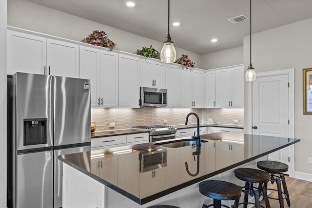 107 Freeman Day Dr, Bastrop, TX 78602 - kitchen with appliances with stainless steel finishes, dark countertops, backsplash, a kitchen bar, and a kitchen island with sink