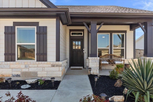 property entrance featuring stone siding, covered porch, board and batten siding, and a shingled roof