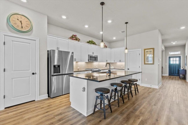 107 Freeman Day Dr, Bastrop, TX 78602 - kitchen featuring stainless steel appliances, a sink, dark countertops, a breakfast bar area, and white cabinetry