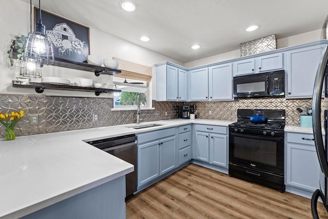 kitchen featuring open shelves, light wood-style flooring, a sink, black appliances, and light countertops