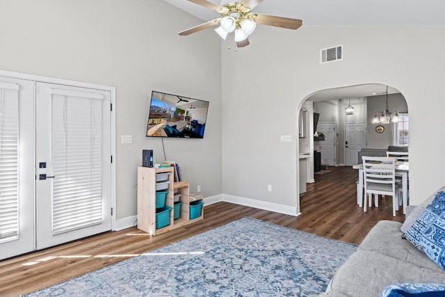 living area with wood finished floors, visible vents, baseboards, arched walkways, and ceiling fan with notable chandelier