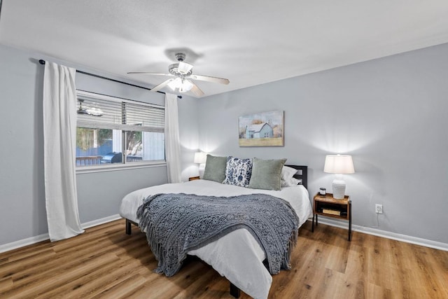 bedroom featuring ceiling fan, baseboards, and wood finished floors