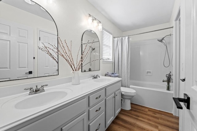 bathroom featuring double vanity, toilet, wood finished floors, and a sink