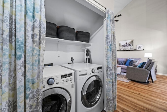 laundry area featuring baseboards, wood finished floors, laundry area, and washer and clothes dryer