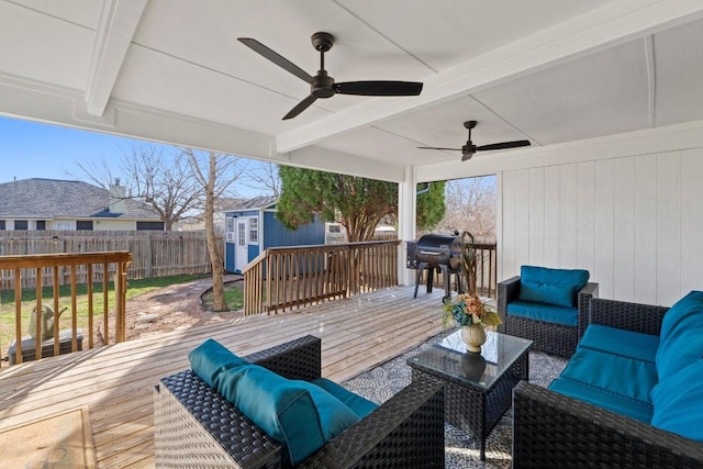 wooden deck featuring a storage unit, an outbuilding, fence, outdoor lounge area, and ceiling fan