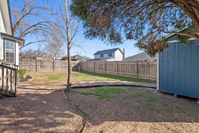 view of yard featuring an outdoor structure, a fenced backyard, and a shed