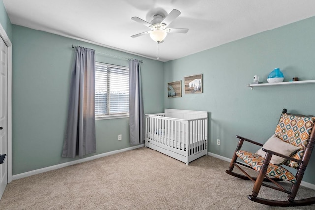 bedroom with a nursery area, ceiling fan, baseboards, and carpet floors